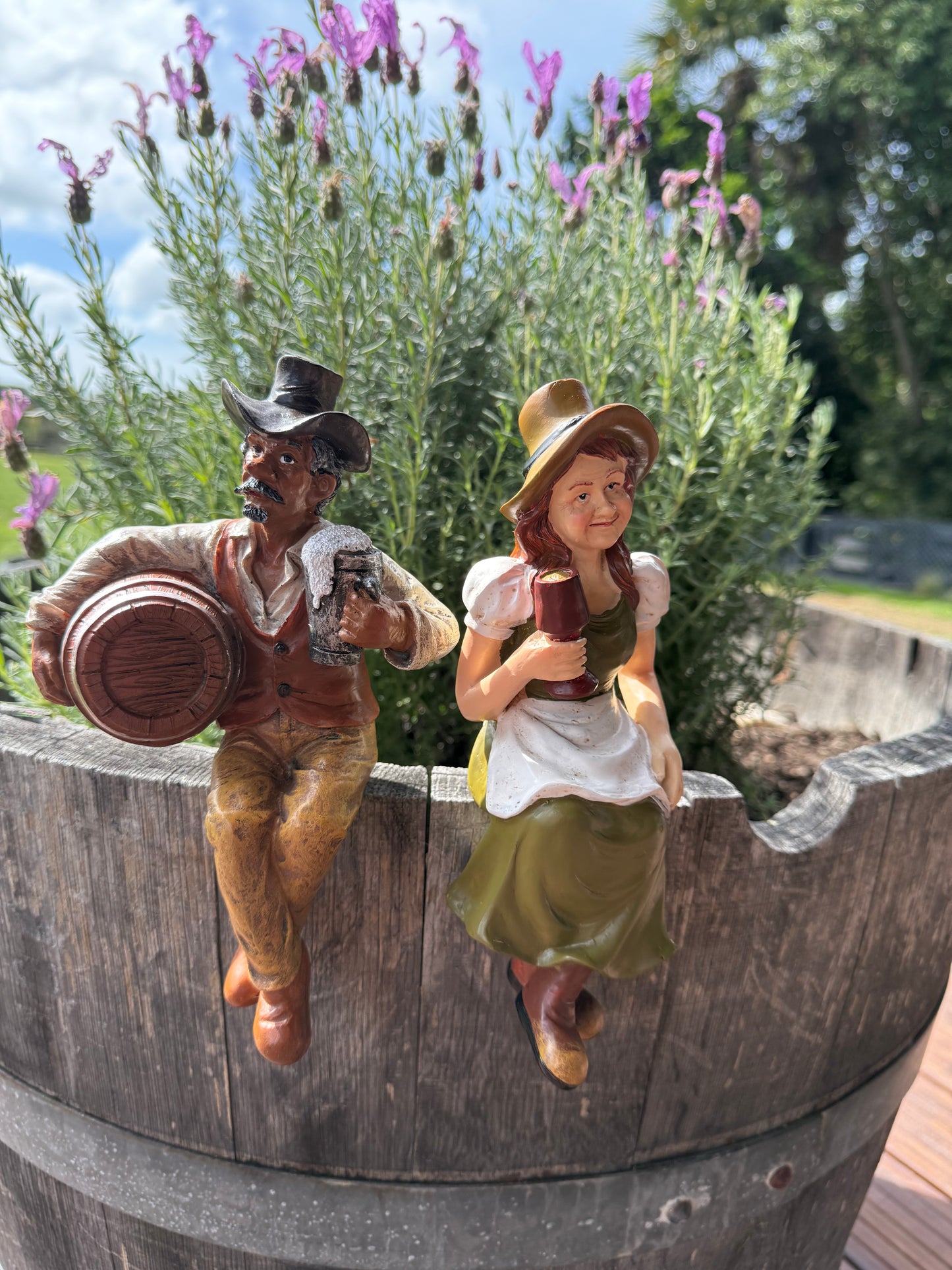 Hand-crafted garden figurine adding character to oak barrel planter